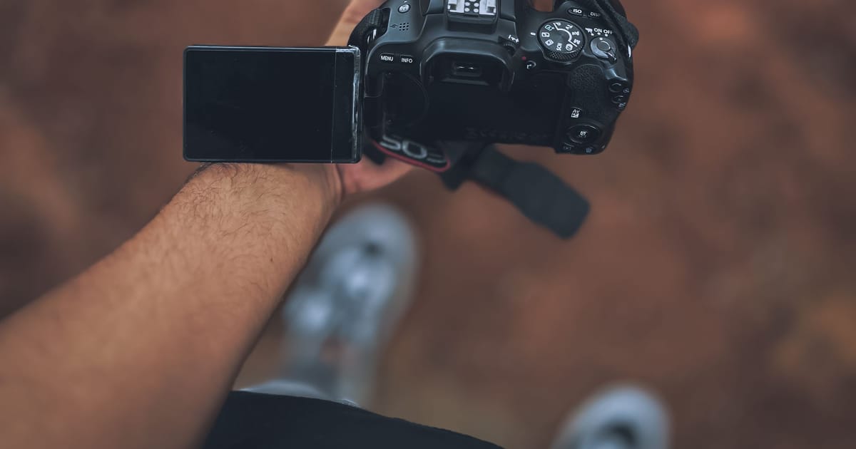 A photographer using a camera with a flip-out screen outdoors