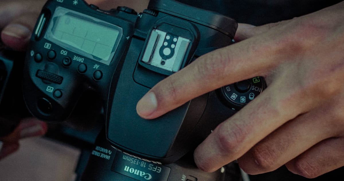 A photographer adjusting settings on a camera outdoors